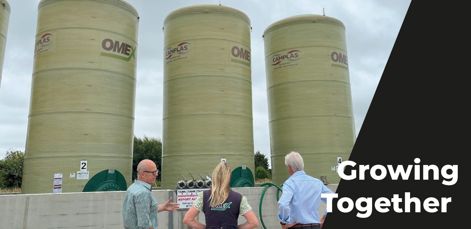 Three people standing in front of liquid fertiliser storage tanks | OMEX